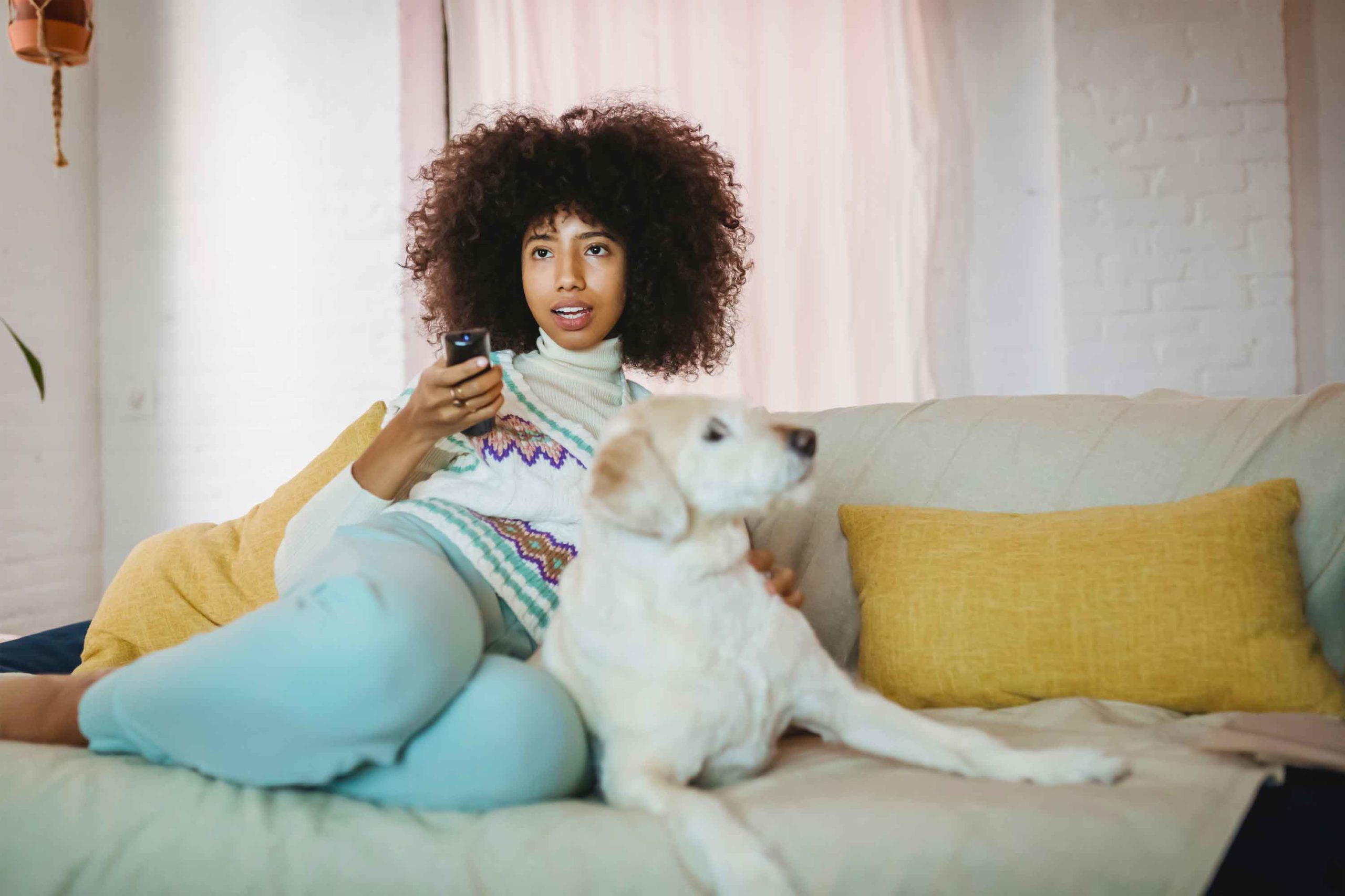 femme sur son canapé devant la télévision avec son chien