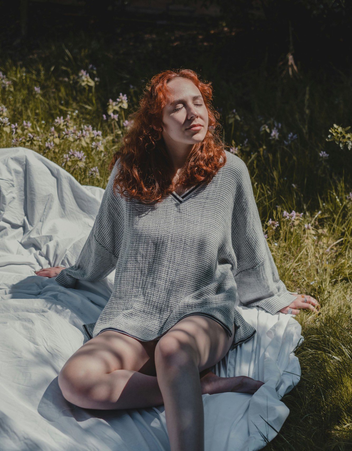 Femme rousse sur un drap dans l'herbe
