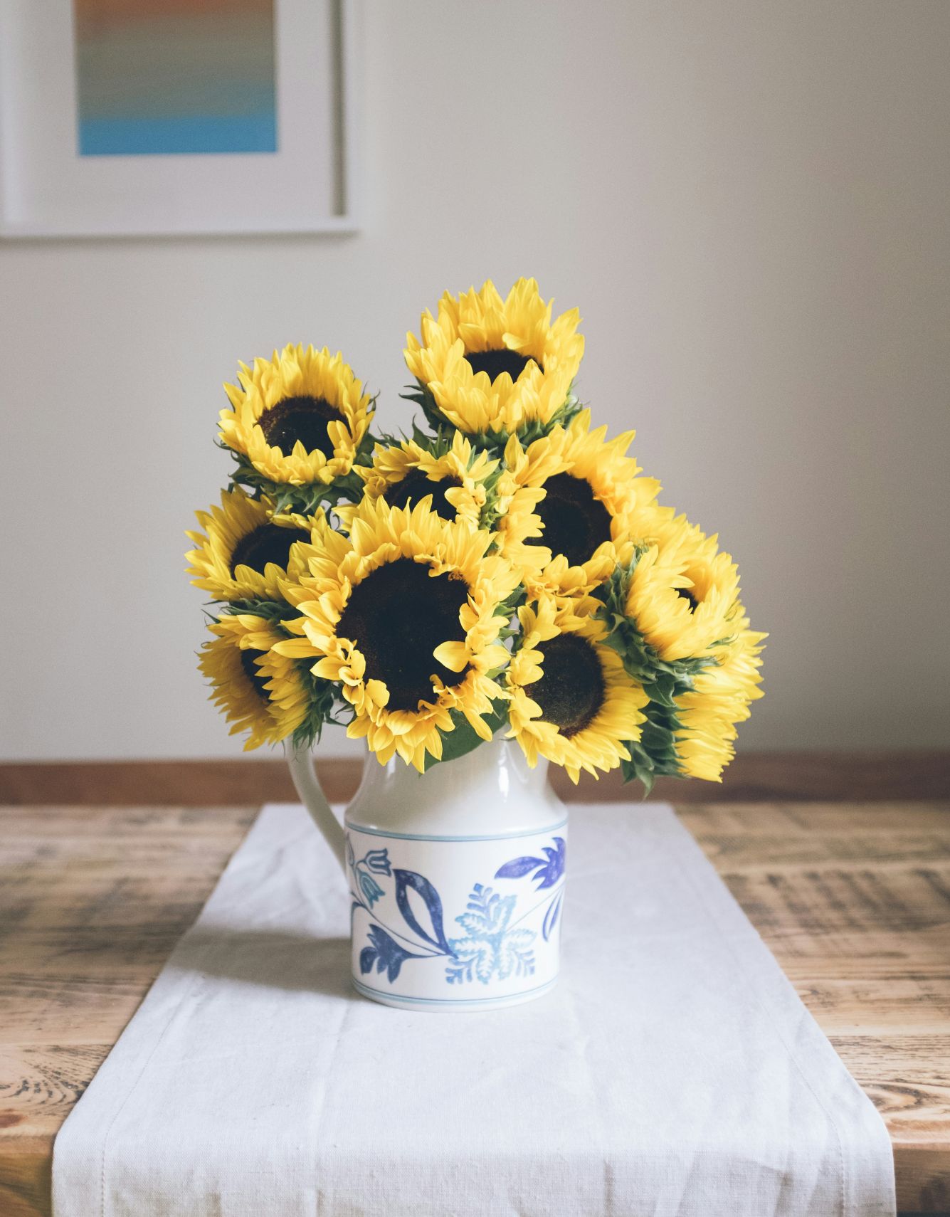 Bouquet de tournesols dans un vase en céramique sur une table en bois, dans un intérieur paisible et lumineux