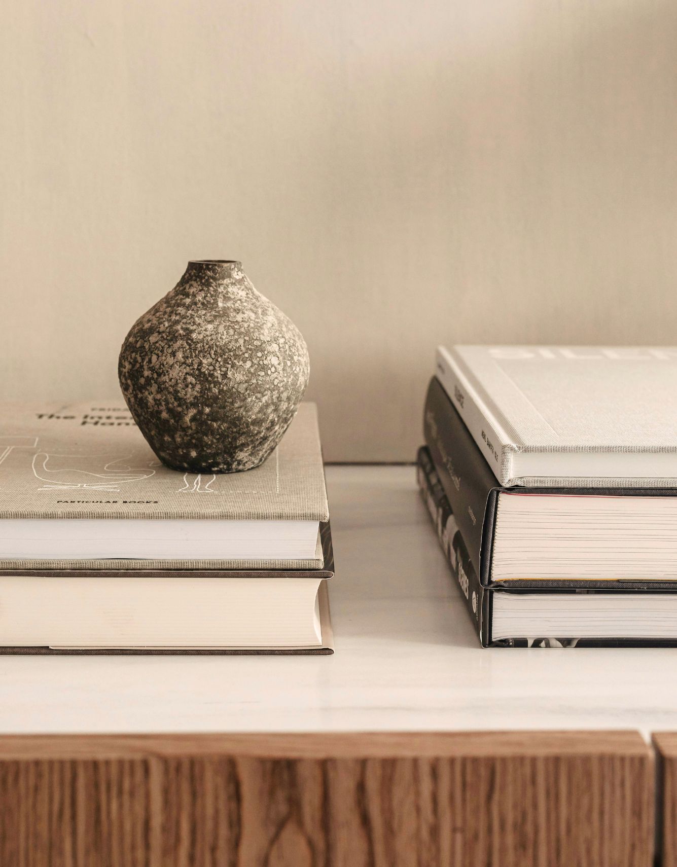 Vase en céramique sur des livres dans un décor minimaliste, illustrant le calme et le lâcher-prise face au perfectionnisme.
